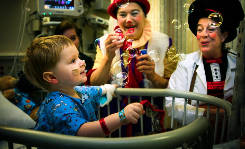 Victoria Millard, left, and Linda Severt, right, captivate patient Karsten Hendricks, 2, with music and bubbles (courtesy of John Curry Photography)