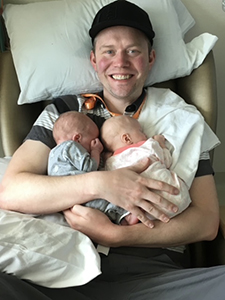 Man holding twin babies to his chest