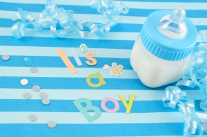 "It's a  boy" sign and baby bottle on blue background