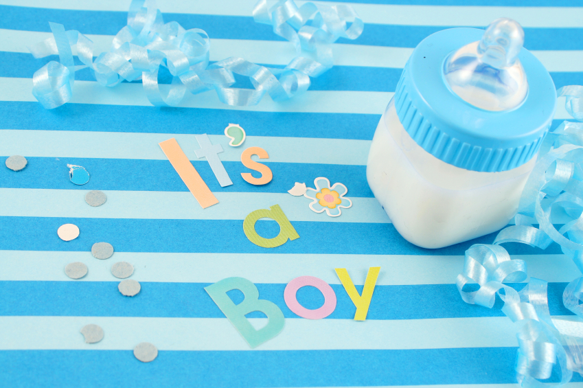 "It's a boy" sign and baby bottle on blue background