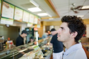 Young man looks at the menu in a fast food restaurant